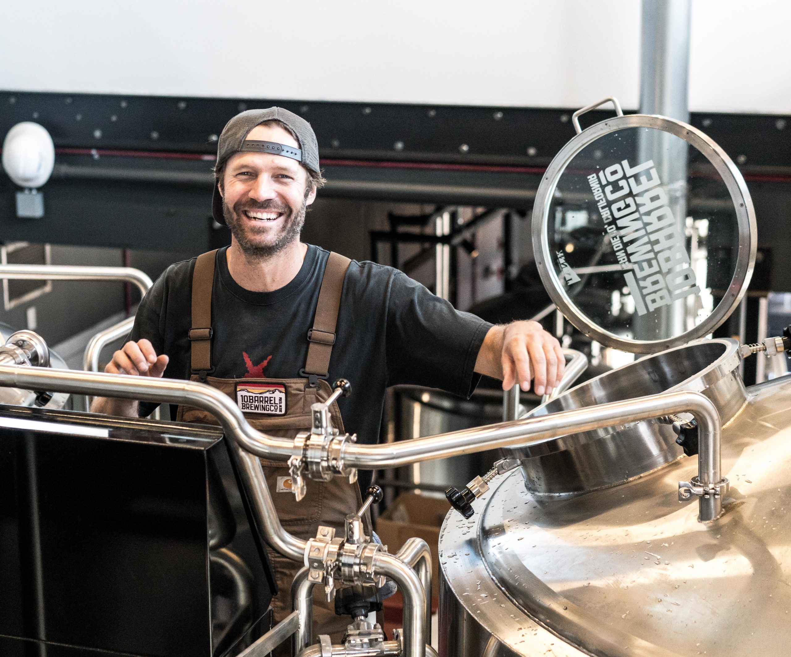 smiling business owner with his brewing equipment on the foreground